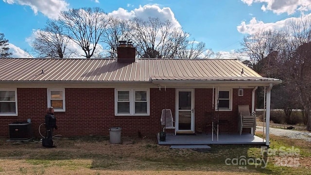 915 Wilkinsville Hwy, Gaffney, SC 29340 - rear view of house featuring brick siding, metal roof, central AC unit, a chimney, and a patio area