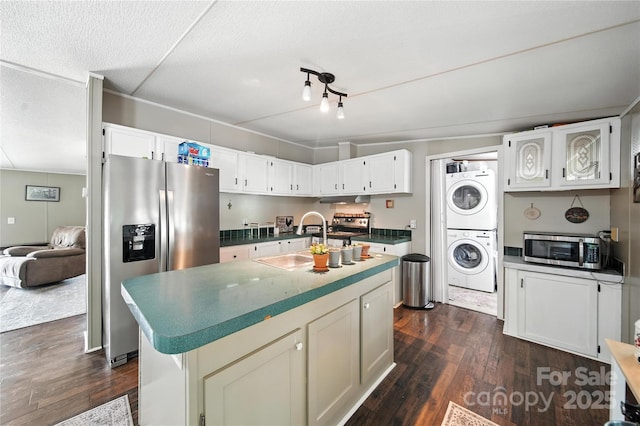 2291 Howell Rd, Midland, NC 28107 - kitchen featuring appliances with stainless steel finishes, stacked washer and clothes dryer, dark wood finished floors, and a center island with sink