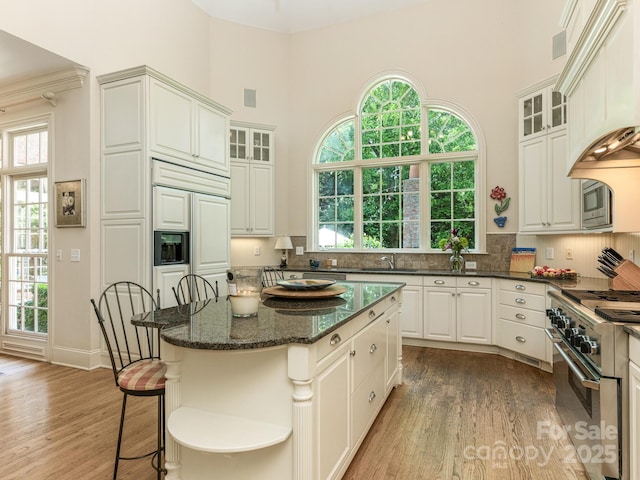 2516 Selwyn Ave, Charlotte, NC 28209 - kitchen with appliances with stainless steel finishes, a high ceiling, light wood finished floors, a kitchen island, and decorative backsplash