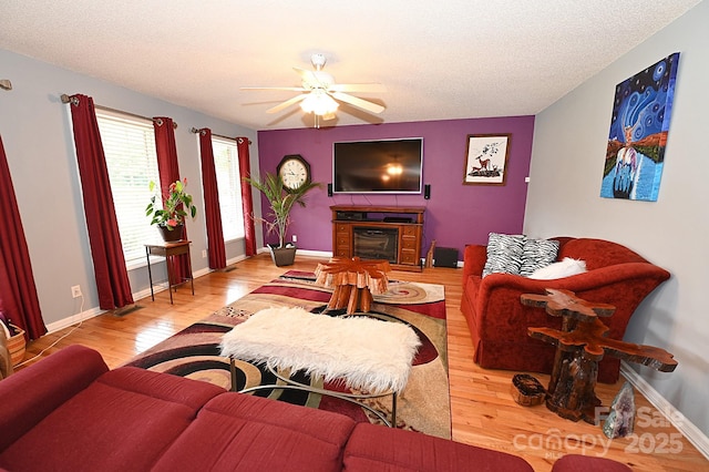 4646 River Run Cir, Hickory, NC 28602 - living area with wood finished floors, a fireplace, ceiling fan, a textured ceiling, and baseboards