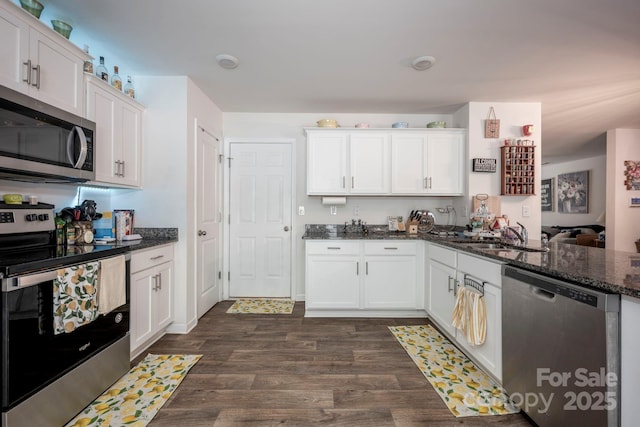7527 Finnigan Rd, Charlotte, NC 28215 - kitchen featuring appliances with stainless steel finishes, a sink, white cabinetry, dark wood-style floors, and dark stone counters