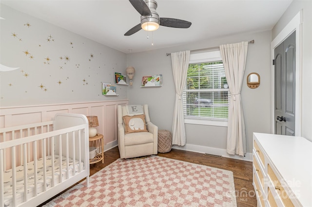 1621 Brookdale Ave, Charlotte, NC 28210 - bedroom with a nursery area, wood finished floors, a wainscoted wall, and a ceiling fan