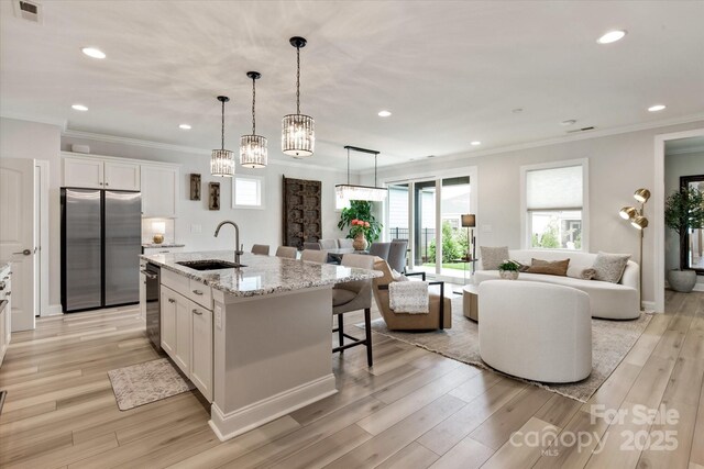 602 Compass Dr, Denver, NC 28037 - kitchen featuring appliances with stainless steel finishes, a sink, open floor plan, white cabinetry, and ornamental molding