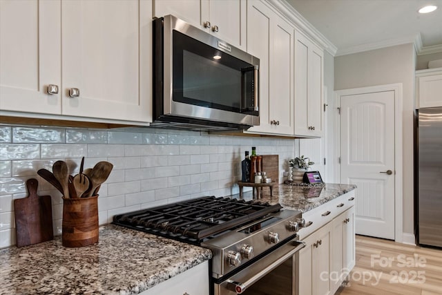 602 Compass Dr, Denver, NC 28037 - kitchen featuring appliances with stainless steel finishes, ornamental molding, white cabinetry, light stone counters, and backsplash