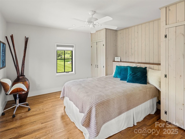 146 Lower Brush Creek Rd, Fletcher, NC 28732 - bedroom featuring baseboards, light wood-style floors, ceiling fan, and wooden walls