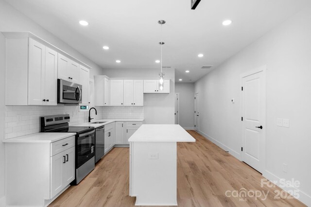 7874 Lucky Creek Ln, Denver, NC 28037 - kitchen featuring stainless steel appliances, a center island, decorative backsplash, a sink, and white cabinetry