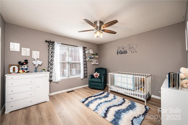 102 Brandywine Dr NE Unit O-3, Conover, NC 28613 - bedroom featuring light wood-style floors, a crib, baseboards, and ceiling fan