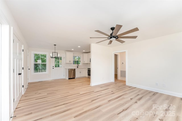 406 N Bostian St, China Grove, NC 28023 - unfurnished living room with light wood-style floors, baseboards, a sink, a ceiling fan, and a chandelier