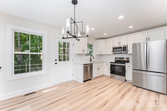 406 N Bostian St, China Grove, NC 28023 - kitchen featuring appliances with stainless steel finishes, a chandelier, light countertops, tasteful backsplash, and white cabinetry