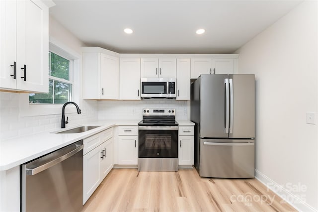 406 N Bostian St, China Grove, NC 28023 - kitchen featuring appliances with stainless steel finishes, a sink, light wood finished floors, white cabinetry, and light countertops