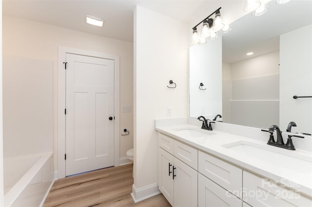406 N Bostian St, China Grove, NC 28023 - bathroom featuring double vanity, toilet, wood finished floors, a bath, and baseboards