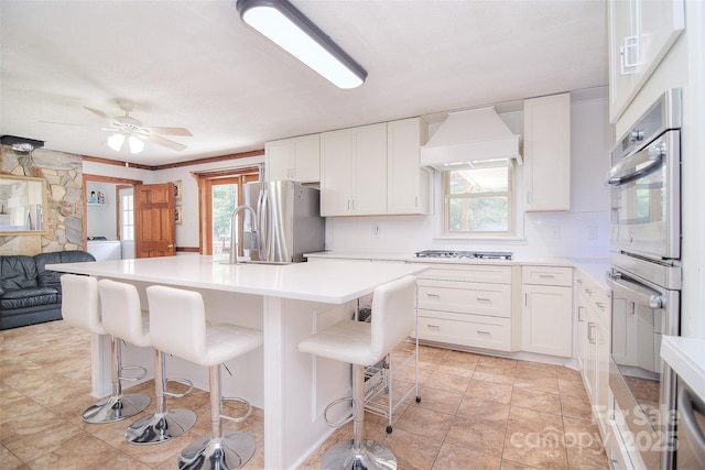 109 Larch Rd, Salisbury, NC 28147 - kitchen with stainless steel appliances, custom range hood, a kitchen island with sink, white cabinets, and light countertops