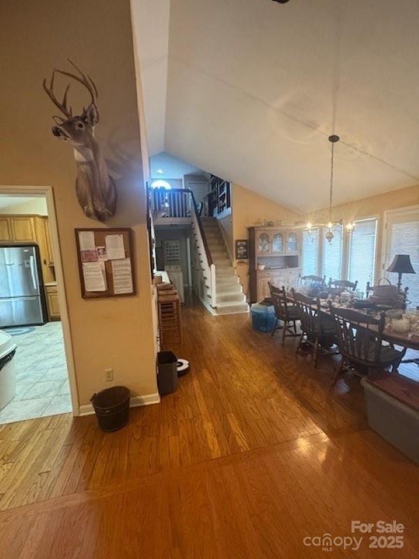 240 Goshen Ter, Wilkesboro, NC 28697 - dining room with lofted ceiling, wood finished floors, stairs, a chandelier, and baseboards