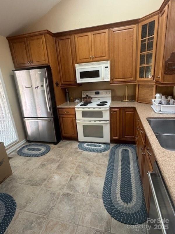 240 Goshen Ter, Wilkesboro, NC 28697 - kitchen featuring appliances with stainless steel finishes, brown cabinetry, vaulted ceiling, and light countertops