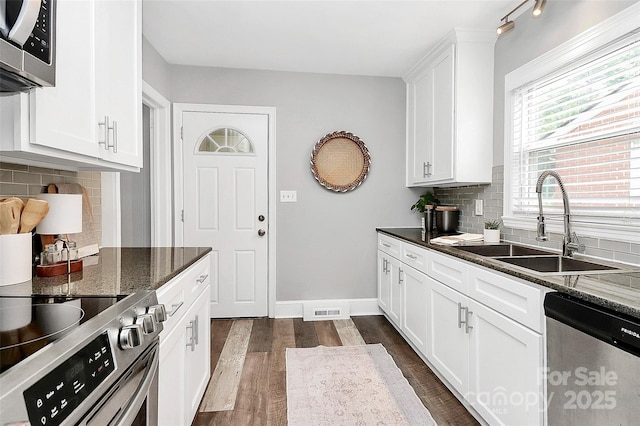 2421 Shamrock Dr, Charlotte, NC 28205 - kitchen with stainless steel appliances, a sink, dark wood finished floors, white cabinetry, and backsplash