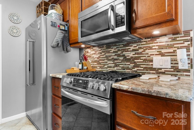 1321 Birch Dr, Morganton, NC 28655 - kitchen featuring stainless steel appliances, light tile patterned floors, brown cabinets, and light stone counters