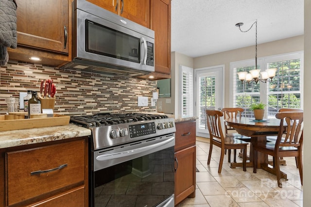 1321 Birch Dr, Morganton, NC 28655 - kitchen featuring appliances with stainless steel finishes, healthy amount of natural light, backsplash, brown cabinets, and a textured ceiling