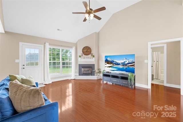 4809 Mossy Cup Ln, Monroe, NC 28110 - living room featuring ceiling fan, a fireplace with raised hearth, wood finished floors, high vaulted ceiling, and baseboards