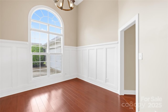 4809 Mossy Cup Ln, Monroe, NC 28110 - spare room with a decorative wall, a chandelier, a wainscoted wall, and dark wood-style floors