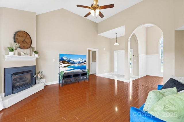 4809 Mossy Cup Ln, Monroe, NC 28110 - living room featuring a towering ceiling, ceiling fan, wood finished floors, a glass covered fireplace, and arched walkways