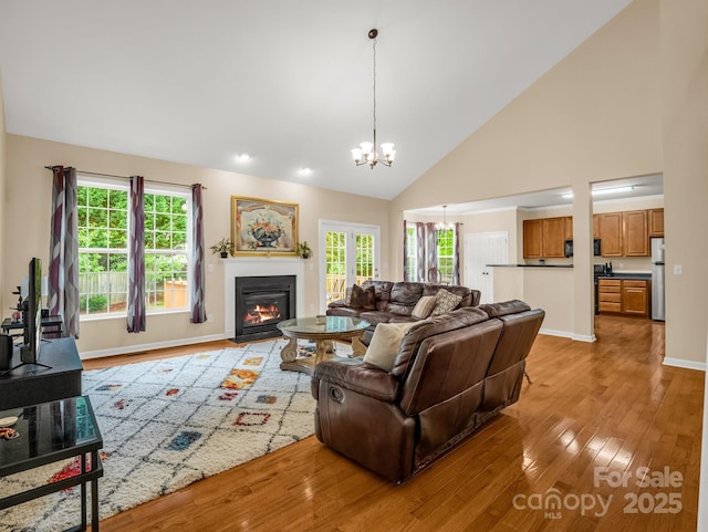 24 Yorktown Cir, Arden, NC 28704 - living room featuring a chandelier, light wood-style floors, a fireplace with flush hearth, high vaulted ceiling, and baseboards
