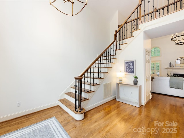5816 Valley Stream Trl, Waxhaw, NC 28173 - stairway with a chandelier, wood finished floors, a high ceiling, baseboards, and a fireplace