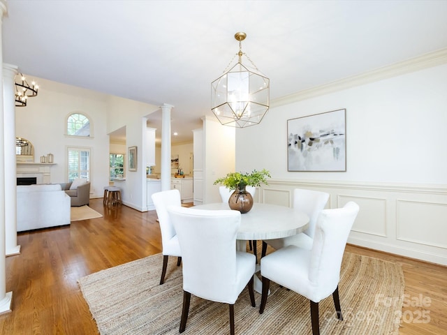 5816 Valley Stream Trl, Waxhaw, NC 28173 - dining space featuring a chandelier, light wood-type flooring, a fireplace, and decorative columns