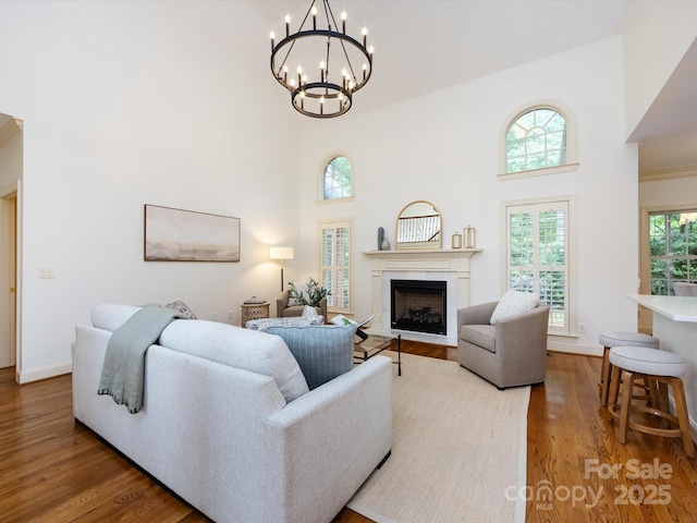 5816 Valley Stream Trl, Waxhaw, NC 28173 - living room featuring a towering ceiling, a fireplace, wood finished floors, a chandelier, and baseboards