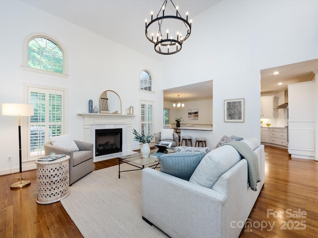5816 Valley Stream Trl, Waxhaw, NC 28173 - living room featuring a chandelier, a towering ceiling, wood finished floors, and a fireplace