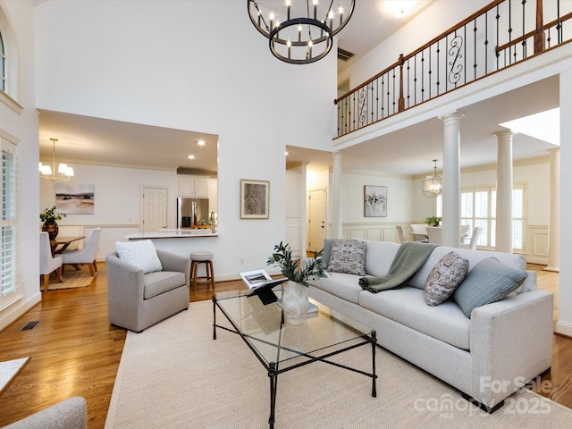 5816 Valley Stream Trl, Waxhaw, NC 28173 - living room featuring a chandelier, a towering ceiling, light wood-type flooring, ornamental molding, and baseboards