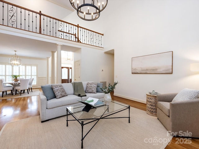 5816 Valley Stream Trl, Waxhaw, NC 28173 - living area with a chandelier, wood finished floors, baseboards, a high ceiling, and ornate columns