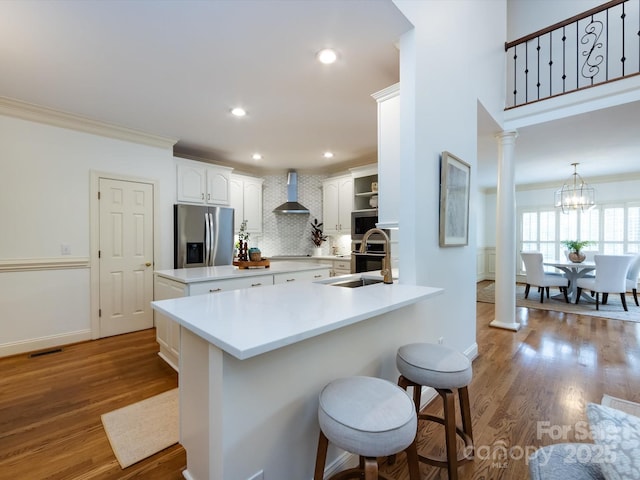 5816 Valley Stream Trl, Waxhaw, NC 28173 - kitchen featuring stainless steel fridge with ice dispenser, wall chimney exhaust hood, a kitchen bar, tasteful backsplash, and wood finished floors