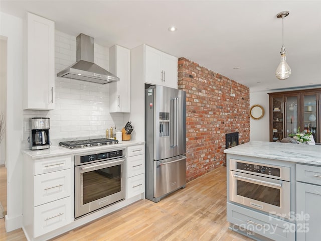6 Browntown Rd, Asheville, NC 28803 - kitchen with stainless steel appliances, wall chimney range hood, decorative backsplash, light wood-type flooring, and brick wall