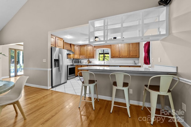 1827 Beckner Rd, Lexington, NC 27292 - kitchen with appliances with stainless steel finishes, brown cabinets, a peninsula, a sink, and a breakfast bar area
