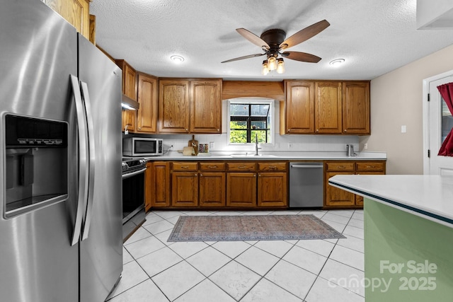 1827 Beckner Rd, Lexington, NC 27292 - kitchen featuring stainless steel appliances, a sink, brown cabinetry, light countertops, and a textured ceiling