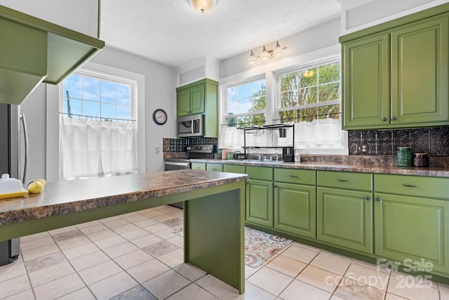 98 S Main St, Granite Falls, NC 28630 - kitchen with appliances with stainless steel finishes, decorative backsplash, light tile patterned floors, a textured ceiling, and dark countertops