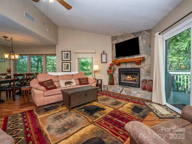 128 Quail Run Ct Unit 1627, Lake Lure, NC 28746 - living area featuring wood finished floors, a textured ceiling, a stone fireplace, plenty of natural light, and lofted ceiling
