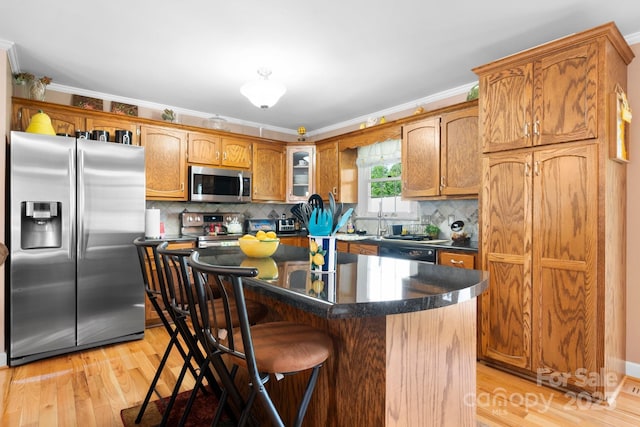10 Hunters Ridge Ct, Granite Falls, NC 28630 - kitchen featuring stainless steel appliances, light wood finished floors, ornamental molding, dark countertops, and a breakfast bar