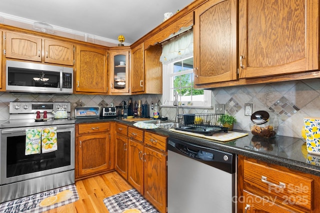 10 Hunters Ridge Ct, Granite Falls, NC 28630 - kitchen with stainless steel appliances, brown cabinetry, light wood-type flooring, backsplash, and crown molding