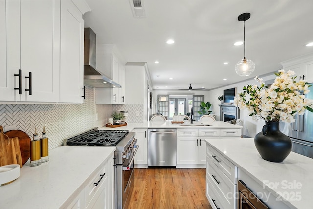 343 Melbourne Ct, Charlotte, NC 28209 - kitchen with stainless steel appliances, wall chimney range hood, a sink, a peninsula, and ceiling fan