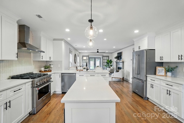 343 Melbourne Ct, Charlotte, NC 28209 - kitchen featuring premium appliances, wall chimney exhaust hood, a peninsula, light countertops, and recessed lighting