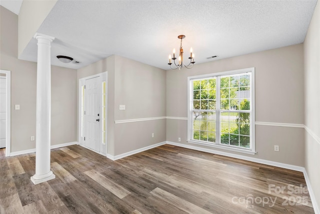 370 Running Briar Rd, Fletcher, NC 28732 - unfurnished dining area with decorative columns, wood finished floors, baseboards, a chandelier, and a textured ceiling