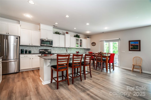 6038 Durango Way, Denver, NC 28037 - kitchen with appliances with stainless steel finishes, a kitchen bar, decorative backsplash, light wood-type flooring, and recessed lighting