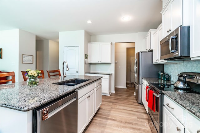 6038 Durango Way, Denver, NC 28037 - kitchen featuring stainless steel appliances, a sink, light wood-style flooring, white cabinetry, and an island with sink