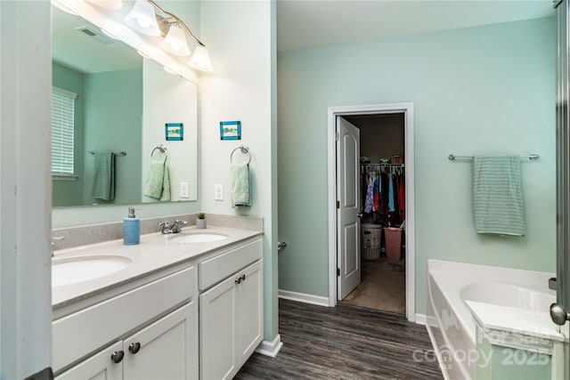 6038 Durango Way, Denver, NC 28037 - full bathroom with wood finished floors, double vanity, a bath, a walk in closet, and baseboards