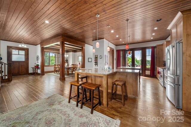 4862 Pinnacle Mountain Rd, Zirconia, NC 28790 - kitchen featuring appliances with stainless steel finishes, wooden ceiling, a breakfast bar area, light stone countertops, and wood-type flooring
