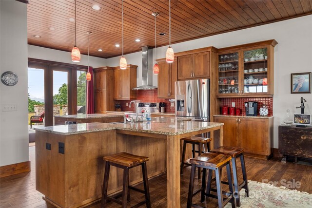 4862 Pinnacle Mountain Rd, Zirconia, NC 28790 - kitchen featuring wall chimney exhaust hood, stainless steel refrigerator with ice dispenser, a center island with sink, brown cabinetry, and wood ceiling