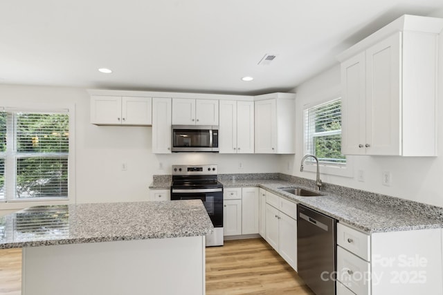 401 W Charlotte Ave, Mount Holly, NC 28120 - kitchen featuring appliances with stainless steel finishes, a sink, white cabinets, light wood-style floors, and recessed lighting
