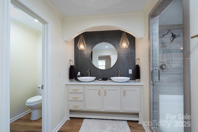 16132 Mclester Rd, Oakboro, NC 28129 - bathroom with double vanity, toilet, a stall shower, wood finished floors, and crown molding