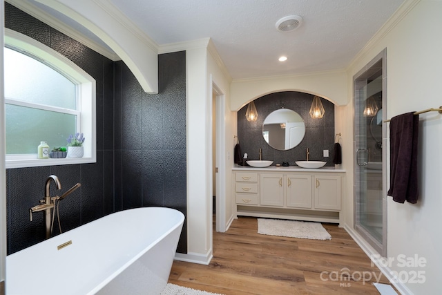 16132 Mclester Rd, Oakboro, NC 28129 - bathroom with double vanity, a freestanding bath, a stall shower, wood finished floors, and crown molding